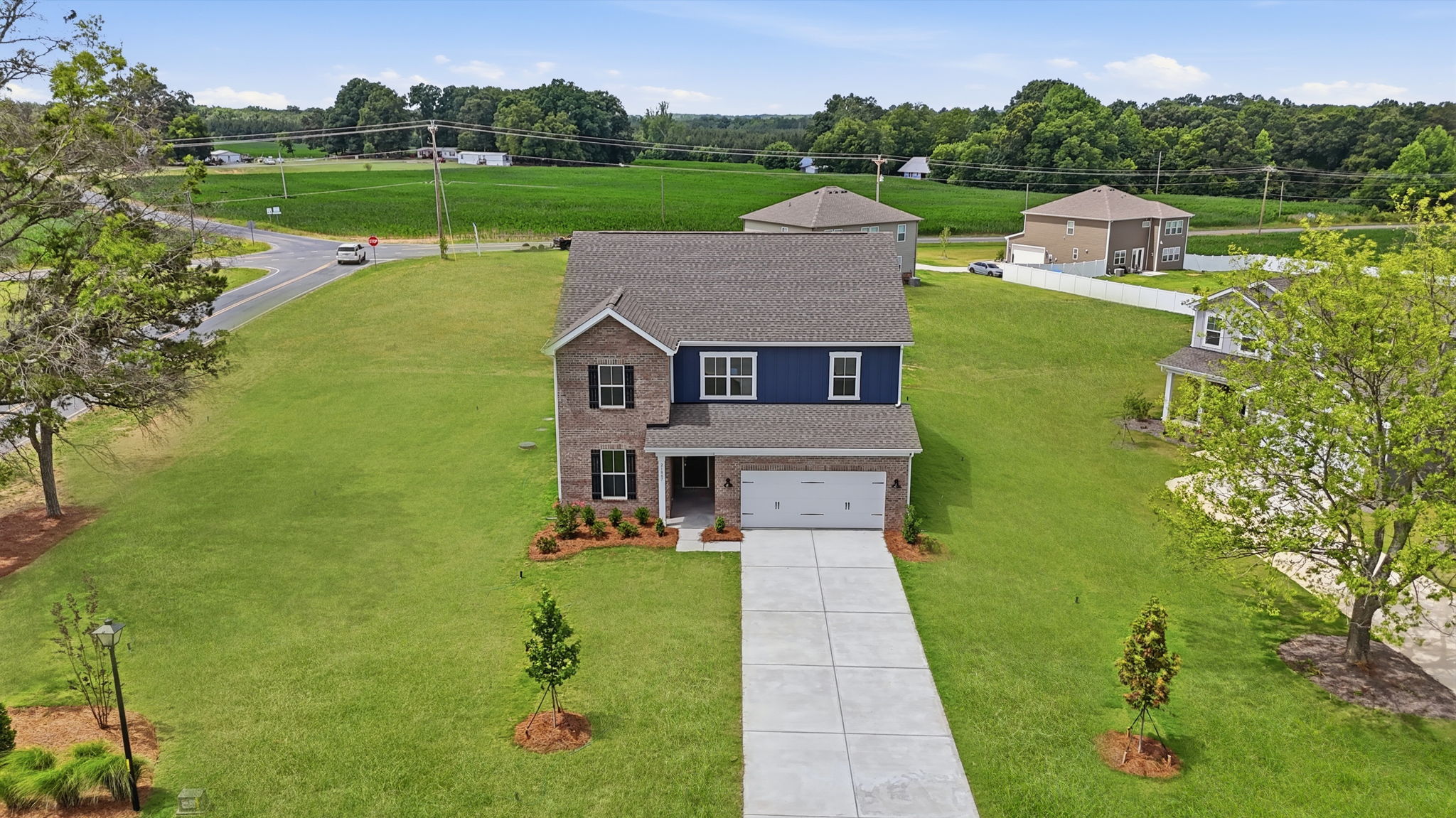 A house with a driveway and a large yard with trees and grass.