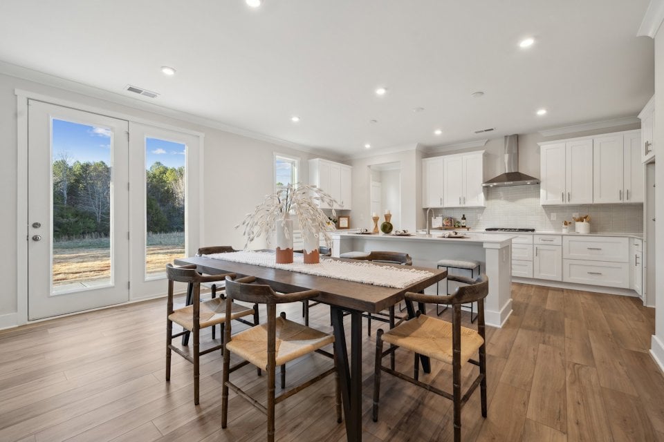 A kitchen with a dining table and chairs.