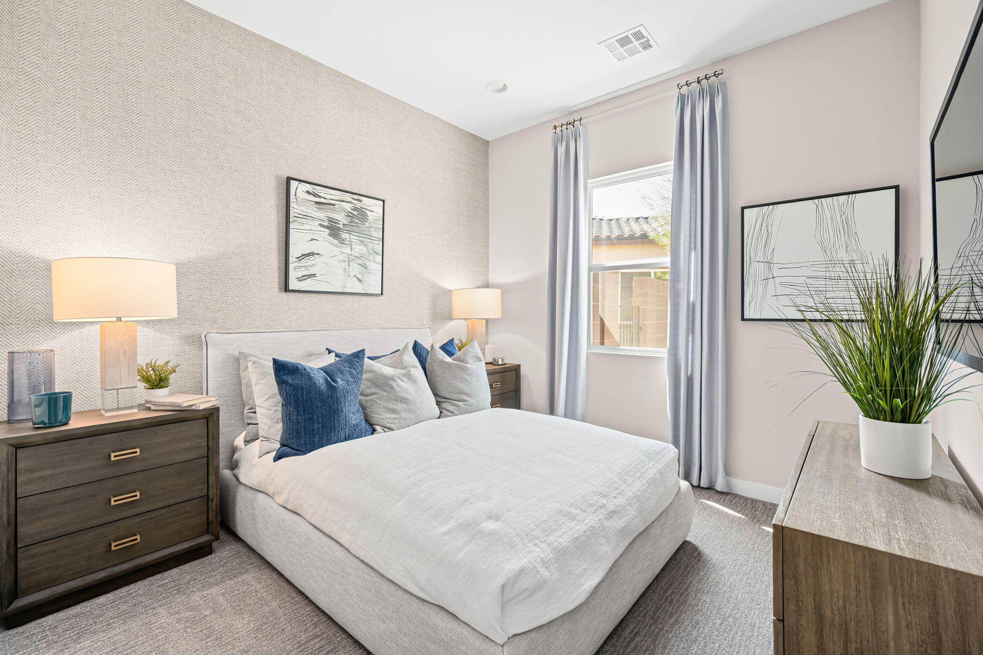 A bedroom with a bed and a plant.