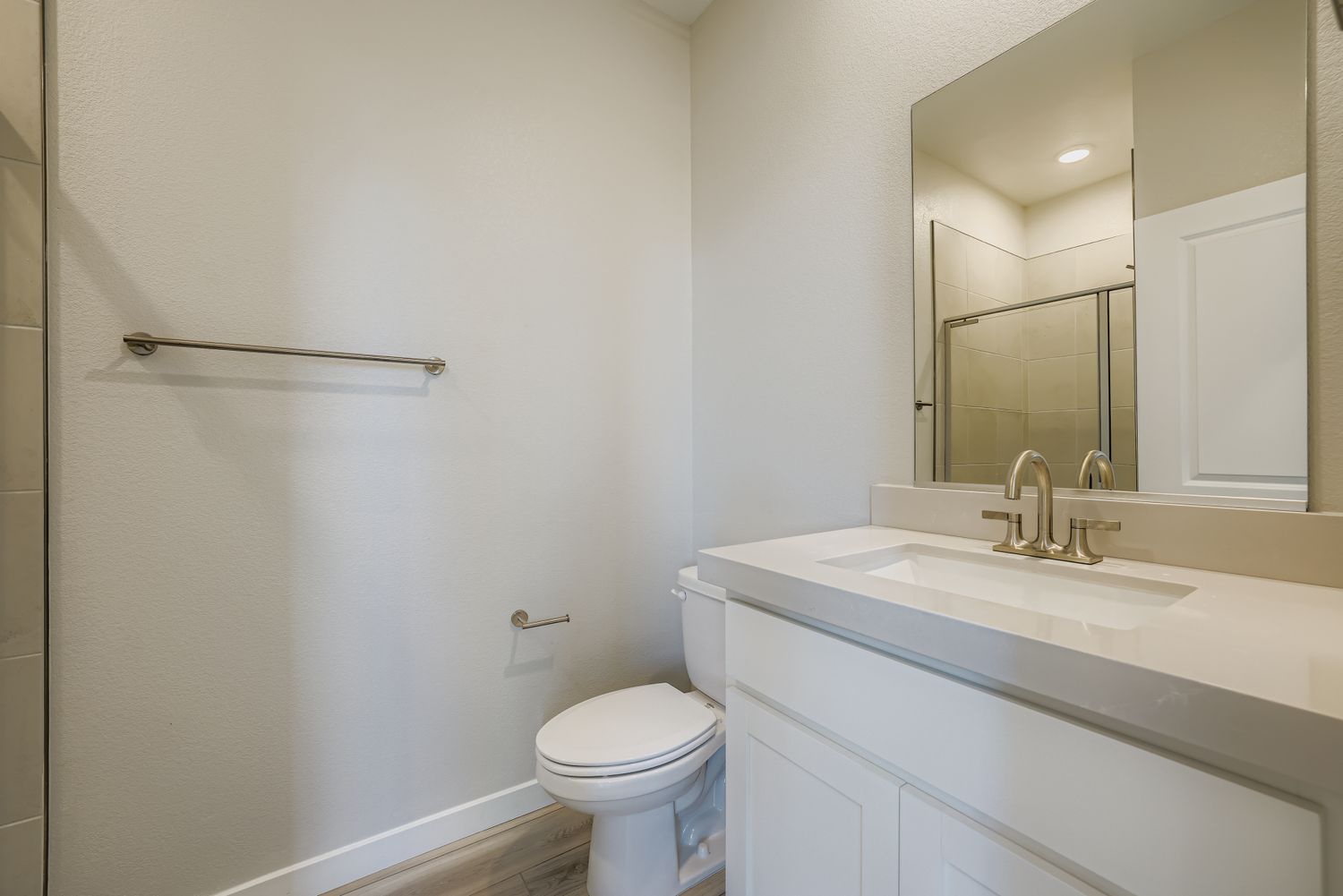 A bathroom with a toilet sink and mirror.