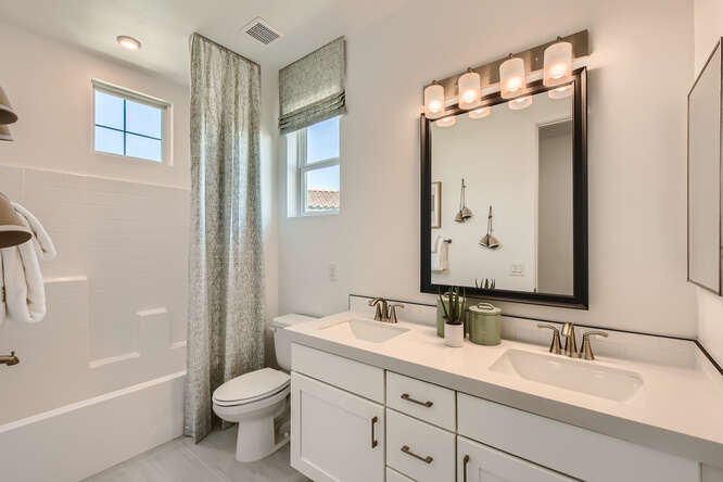 A bathroom with a sink toilet and mirror.