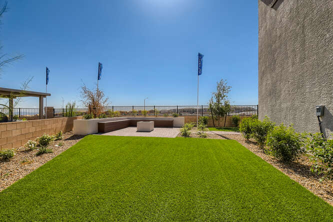 A grassy area with a fence and a building in the background.