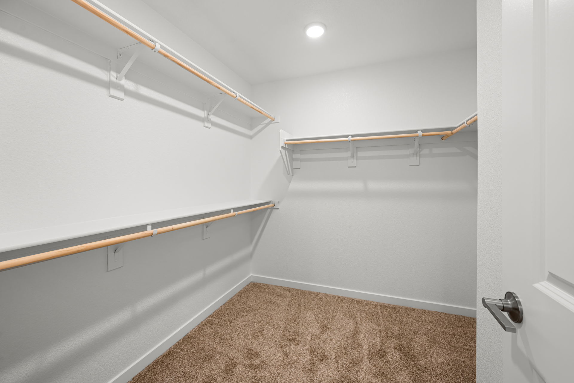 A hallway with a carpet and a metal railing.