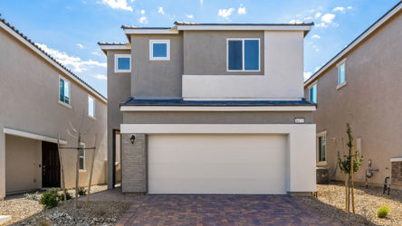 A white garage with a brick driveway.