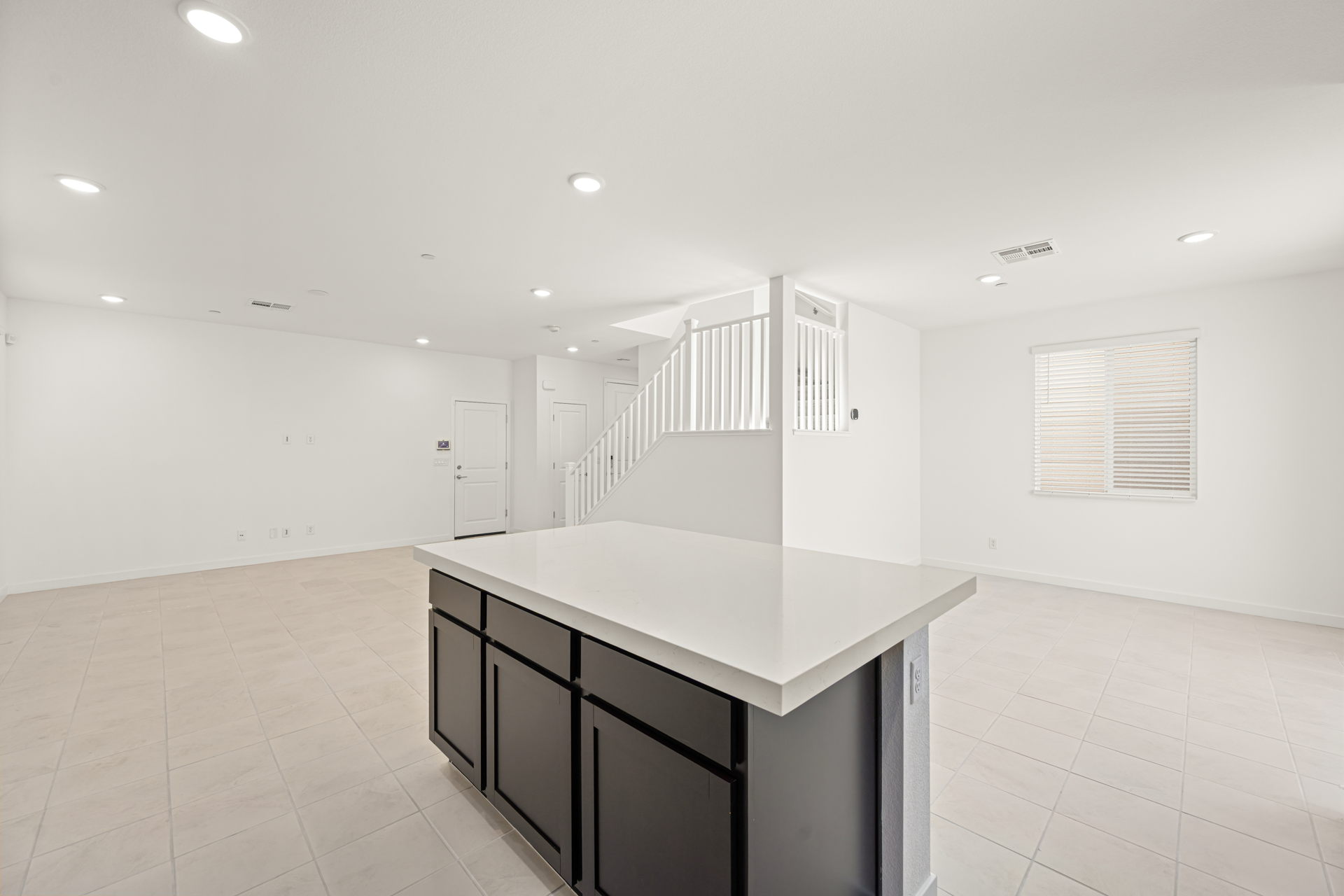 A room with a white counter and a white staircase.