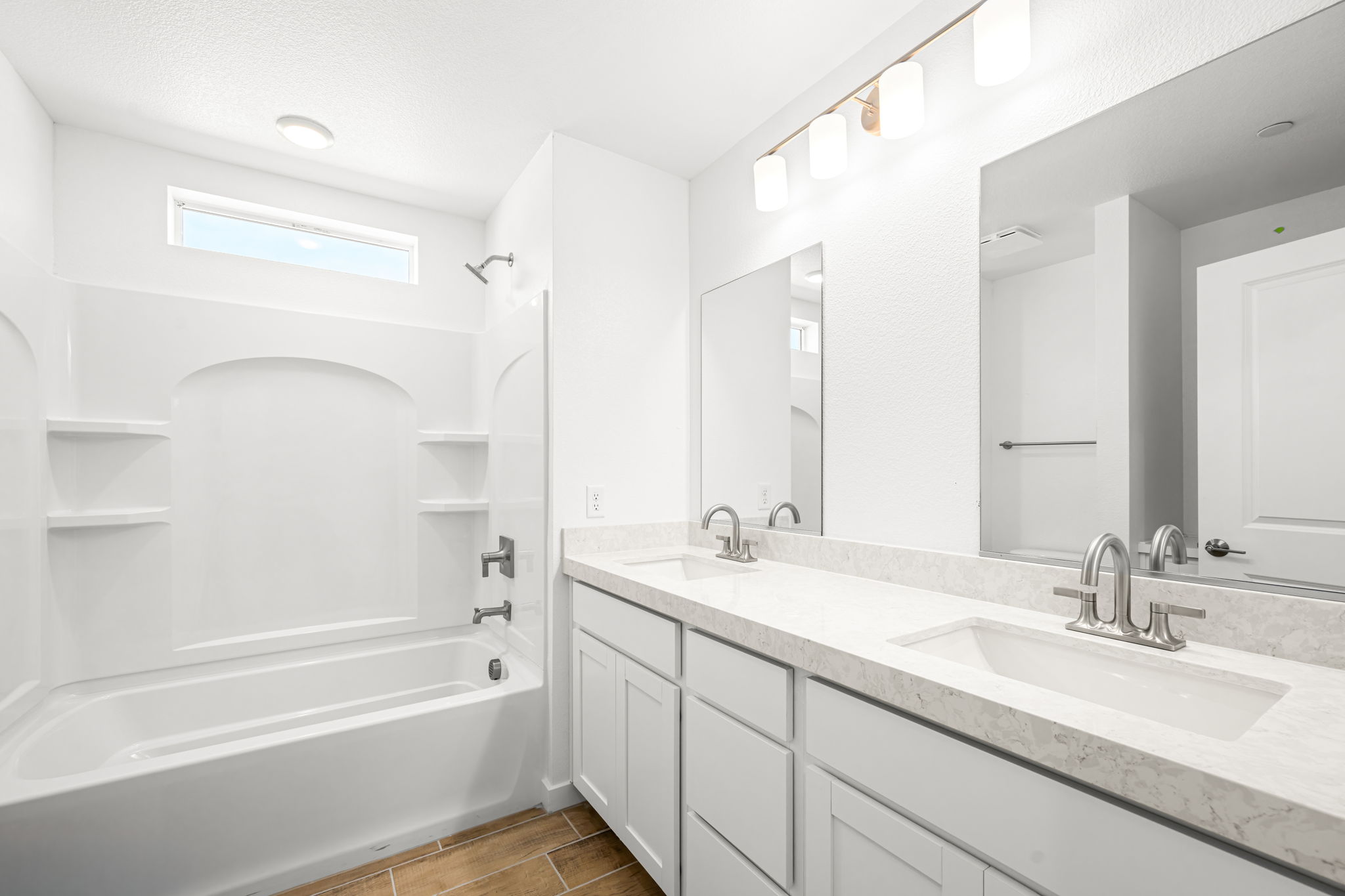 A bathroom with a tub sink and mirror.