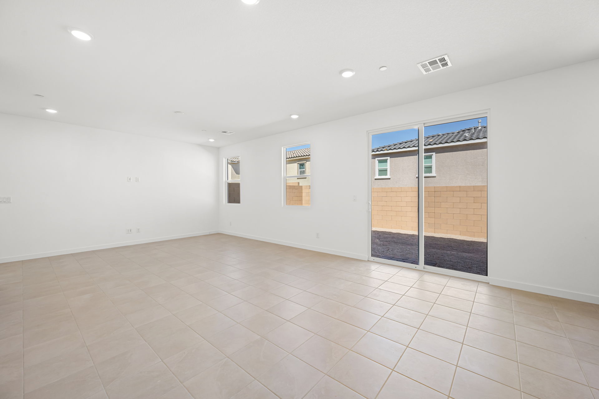 A large empty room with a tile floor and a glass door.