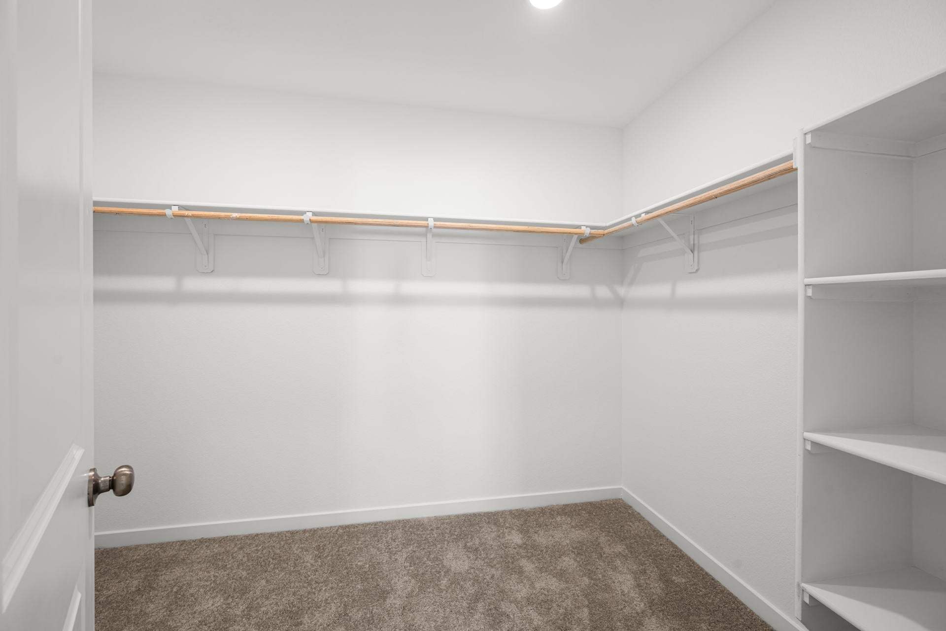 A white room with a white wall and a brown carpet.