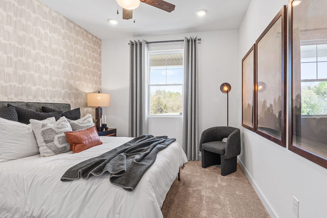 A bedroom with a bed and a chair.