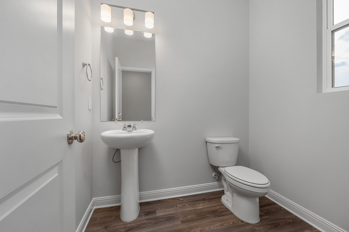 A bathroom with a sink toilet and mirror.