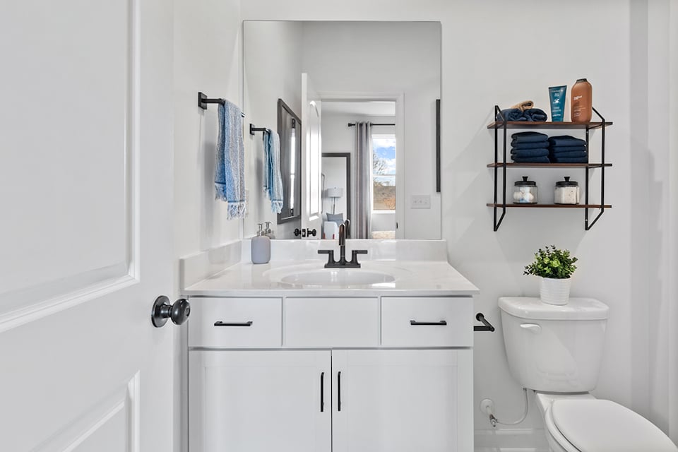 A bathroom with a sink toilet and mirror.