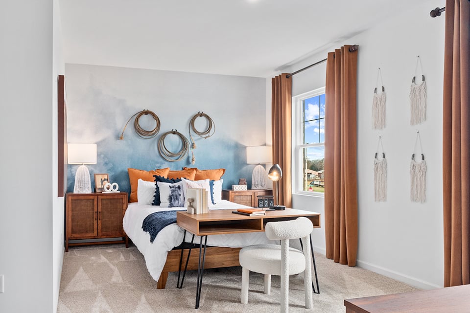 A bedroom with a bed desk and a mirror.