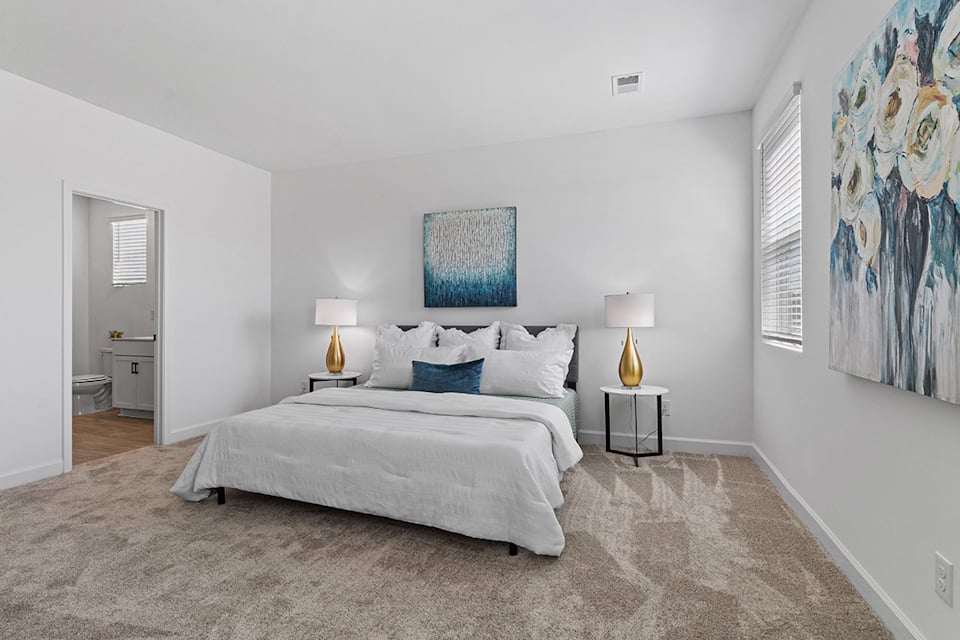 A bedroom with a bed and lamps.