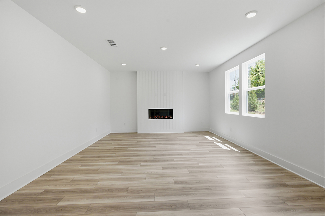 A room with a wood floor and a television on the wall.