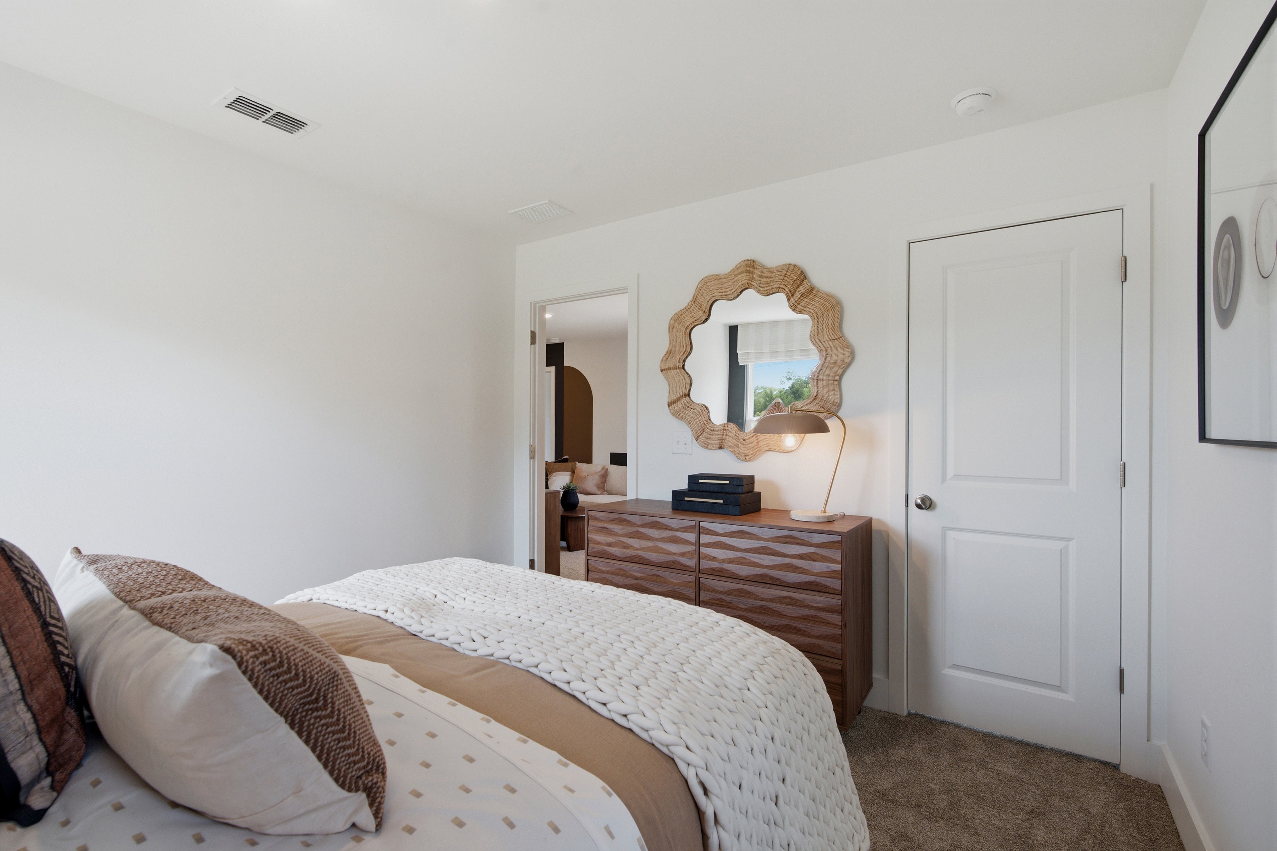 A bedroom with a mirror and a bed.