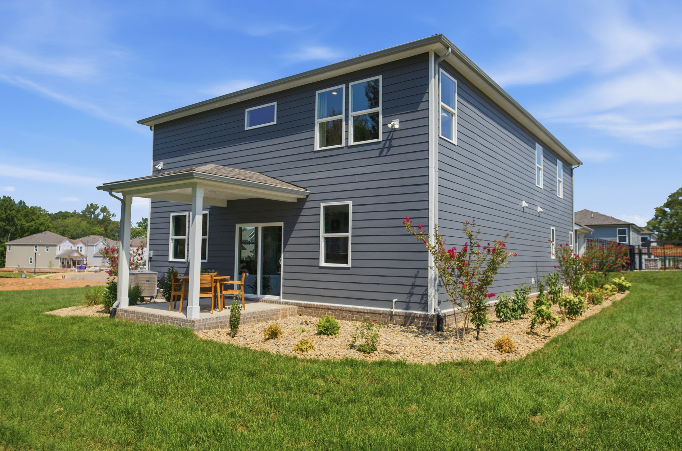 A house with a yard and a table and chairs in the front.