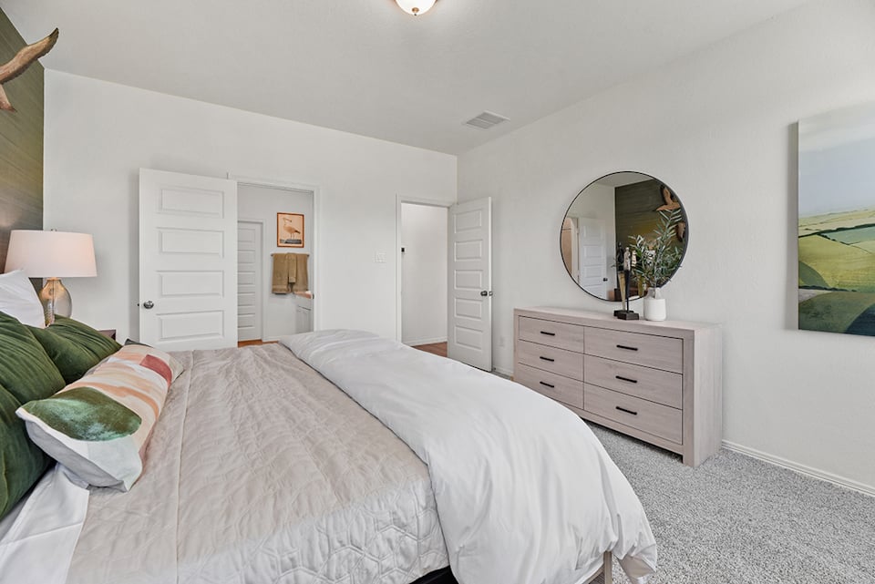 A bedroom with a bed and a mirror.