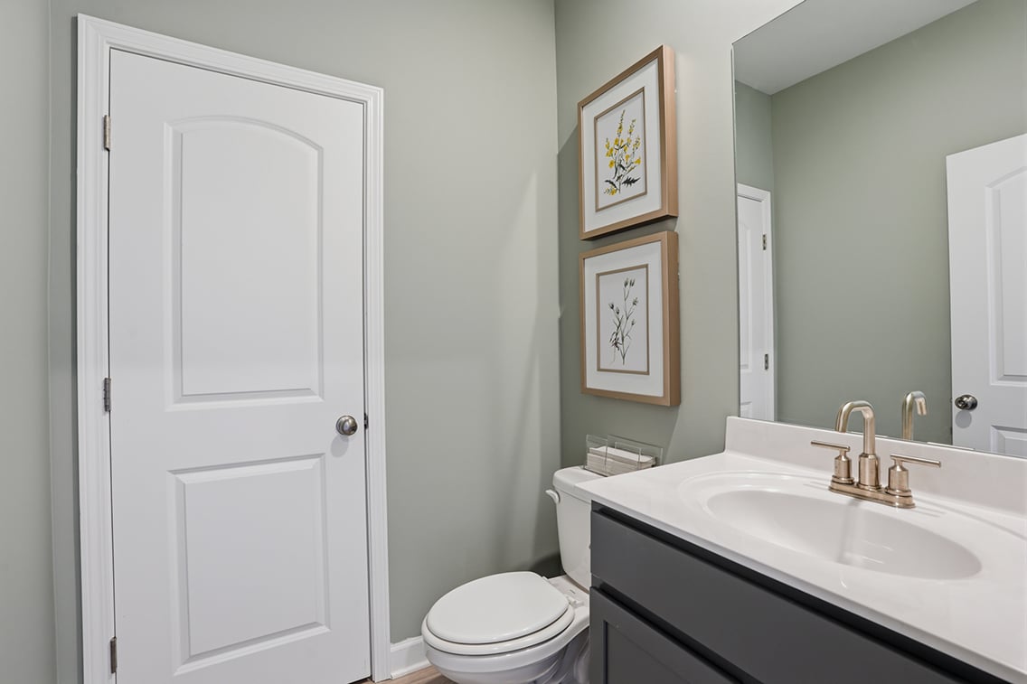 A bathroom with a sink toilet and a mirror.