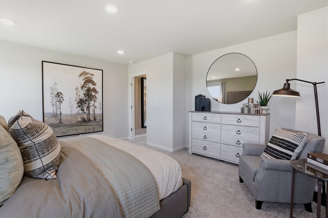 A bedroom with a bed and a chair.