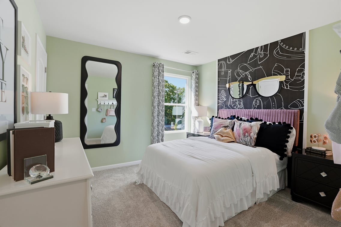 A bedroom with a bed and a mirror.