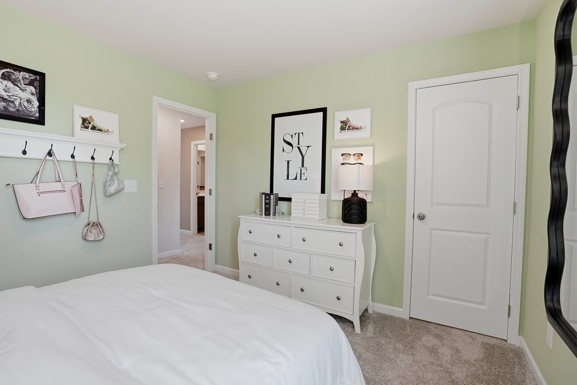 A bedroom with a white bed and white cabinets.