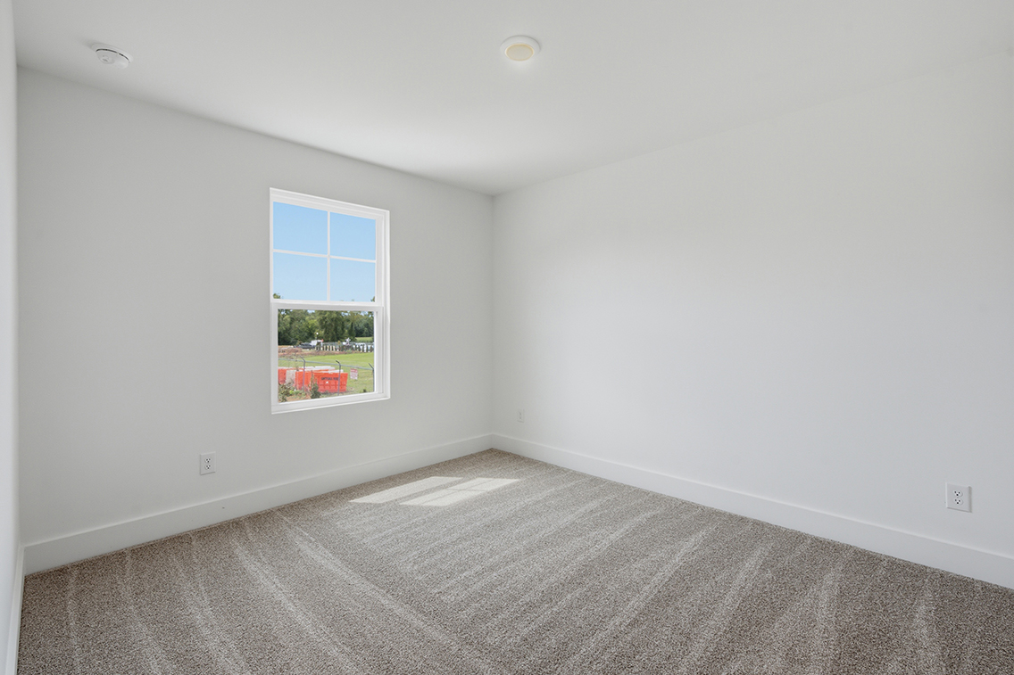 A room with a window and a rug.