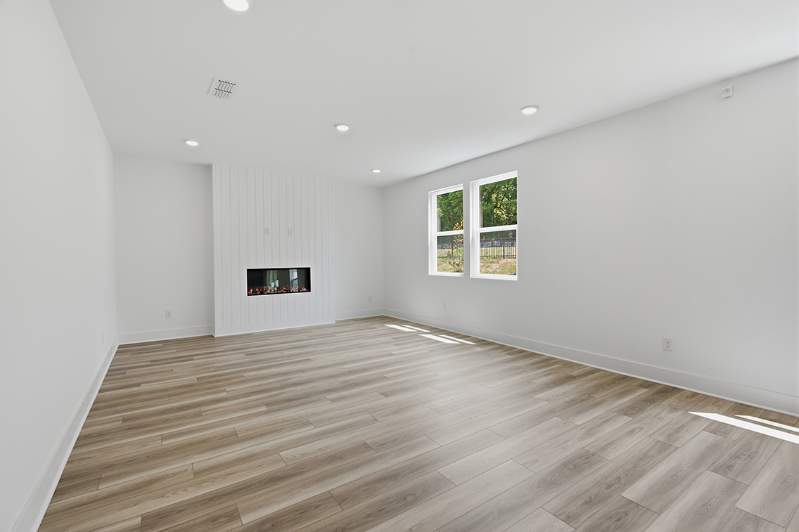 A room with a wood floor and a television on the wall.
