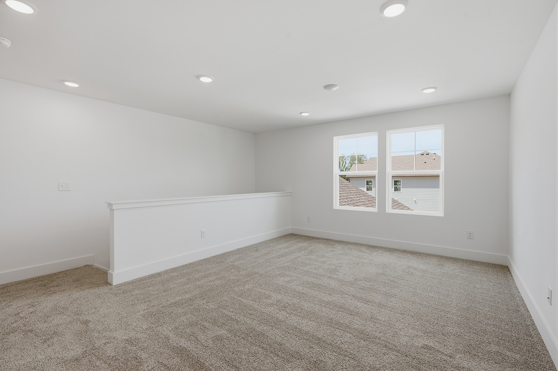 A room with a carpet and a white wall with a window.