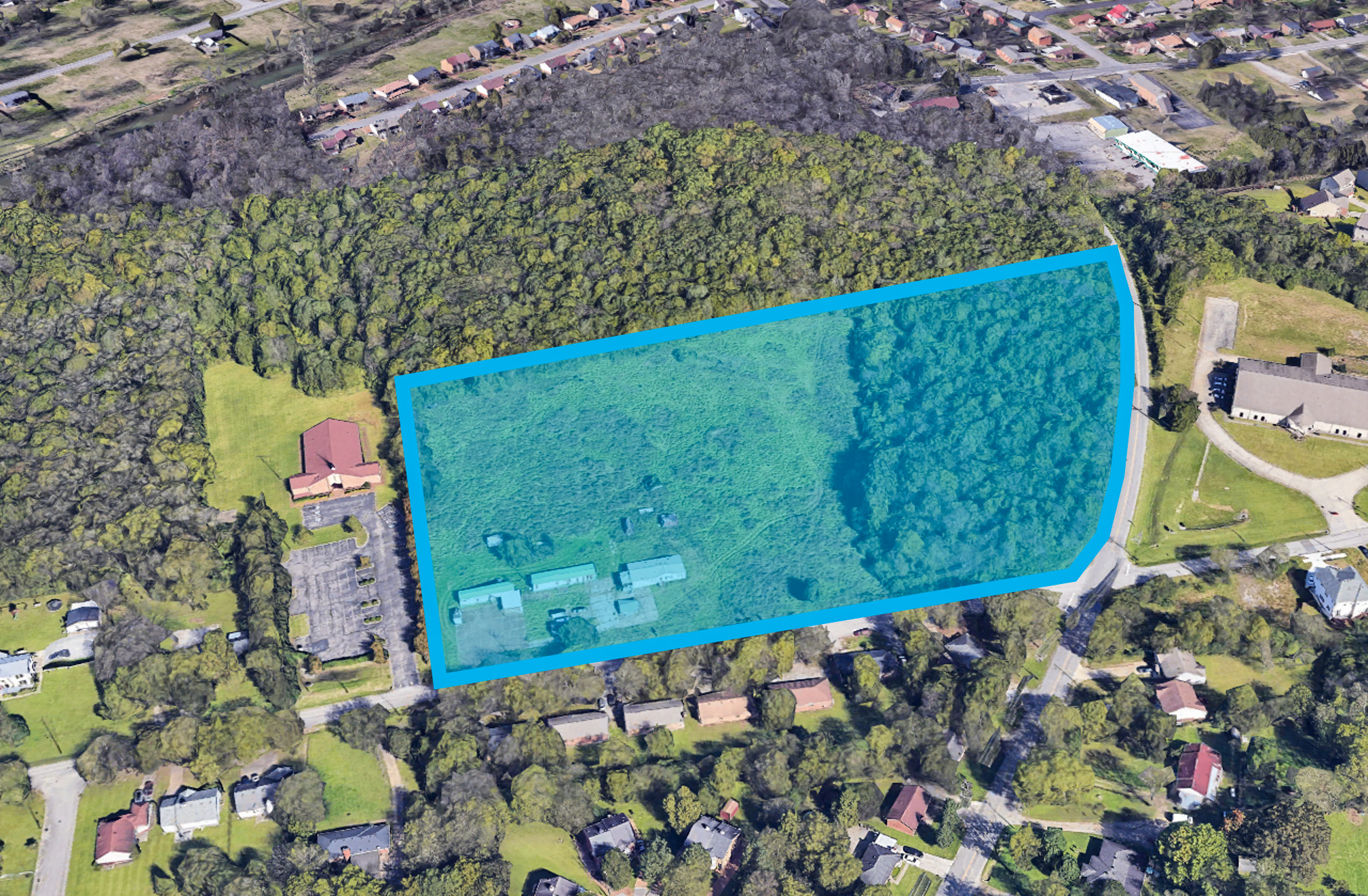 A large green field with buildings and trees around it.