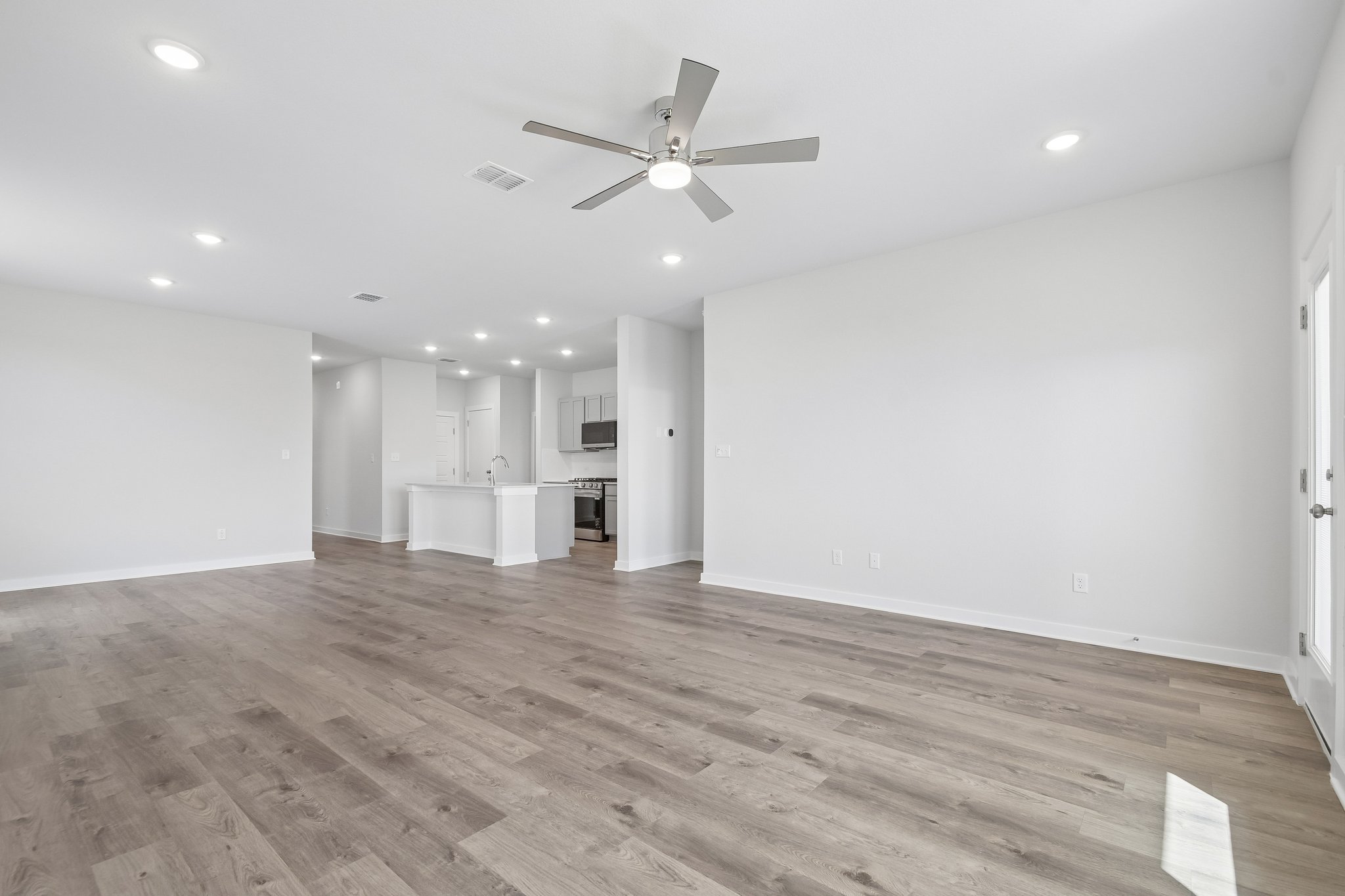 A large empty room with a ceiling fan and a wood floor.