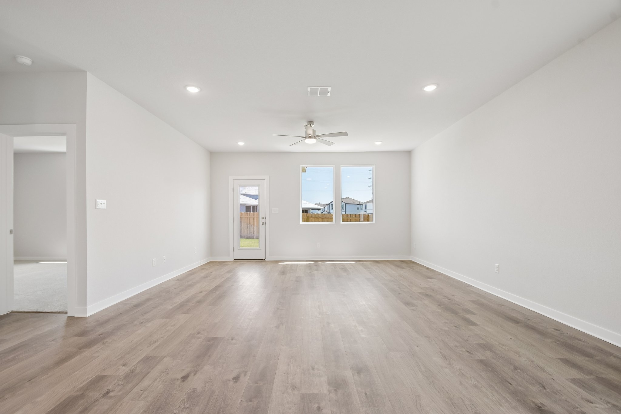A room with a wood floor and a wood floor with a ceiling fan.