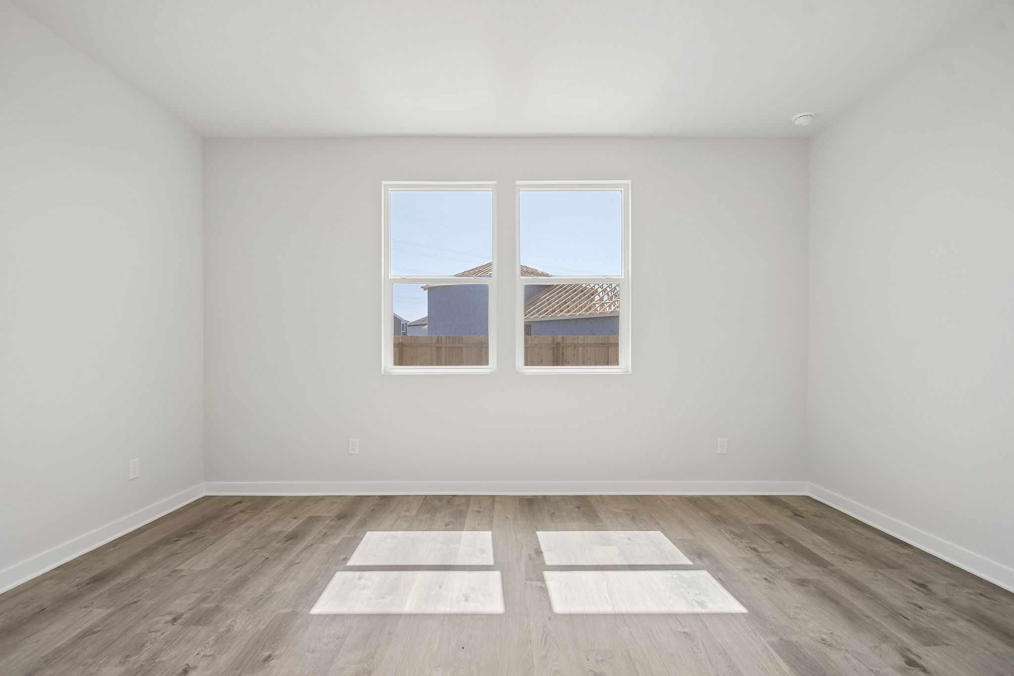 A room with a wood floor and a window with a view of the city.