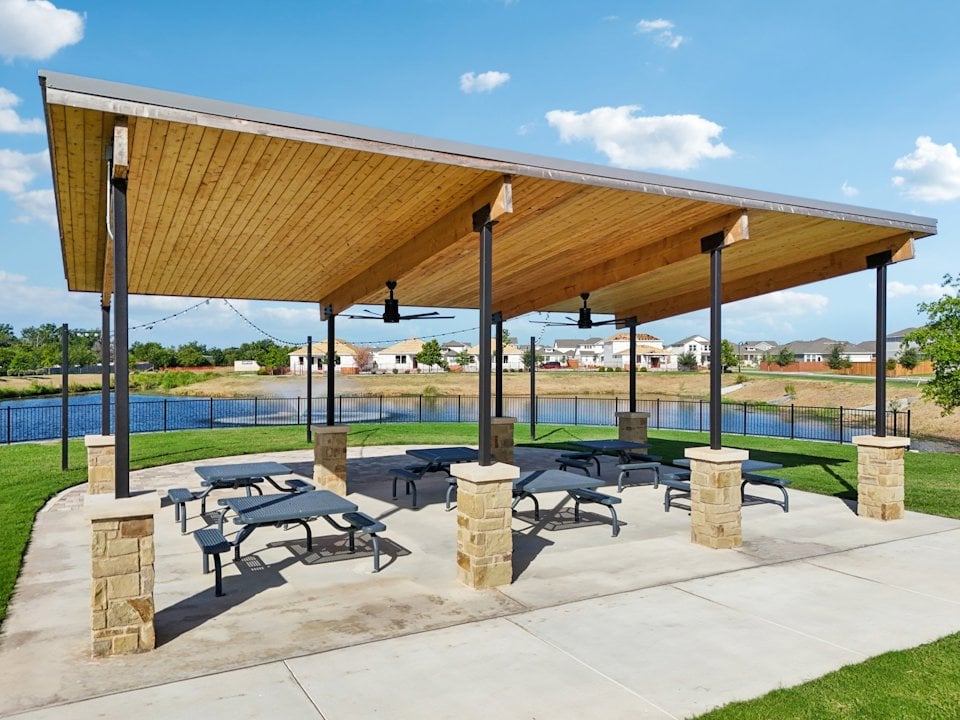A covered area with benches and a body of water in the background.