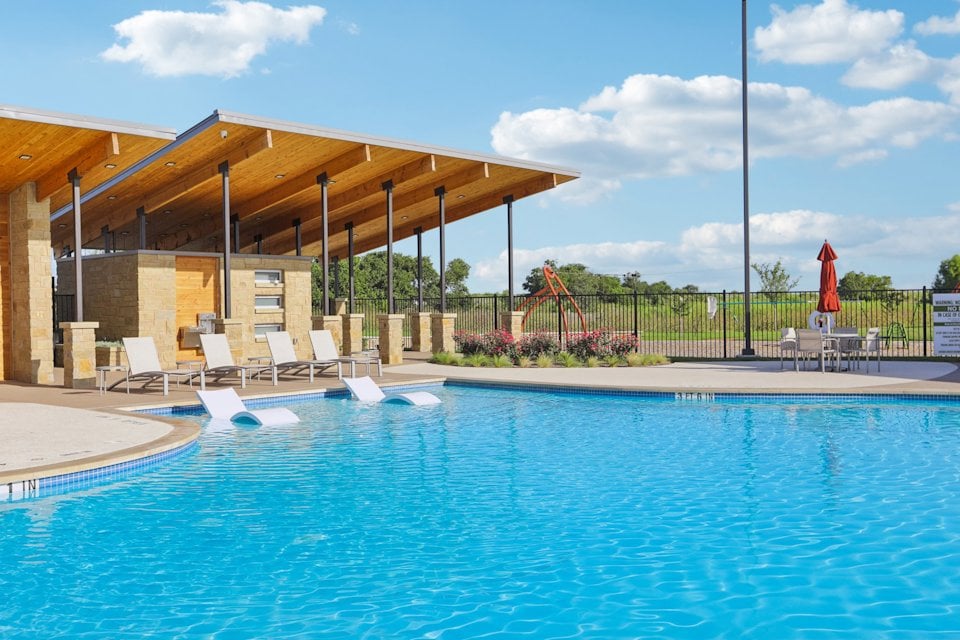 A swimming pool with chairs and umbrella.