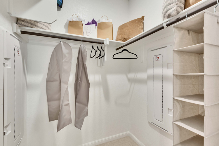 A white shelving unit with white shelves and a white wall with a brown pillow and a brown.