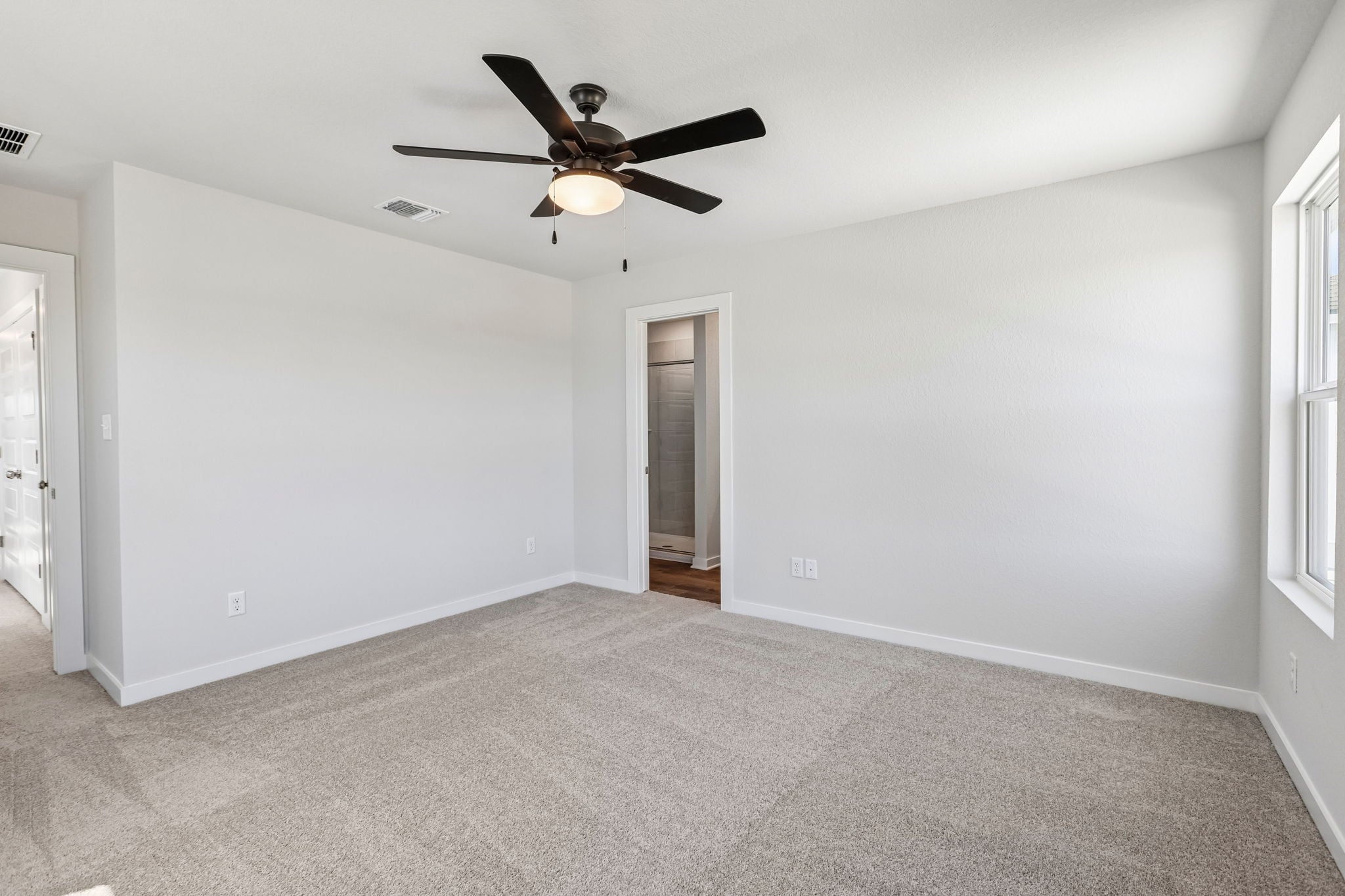 A room with a ceiling fan and a door.