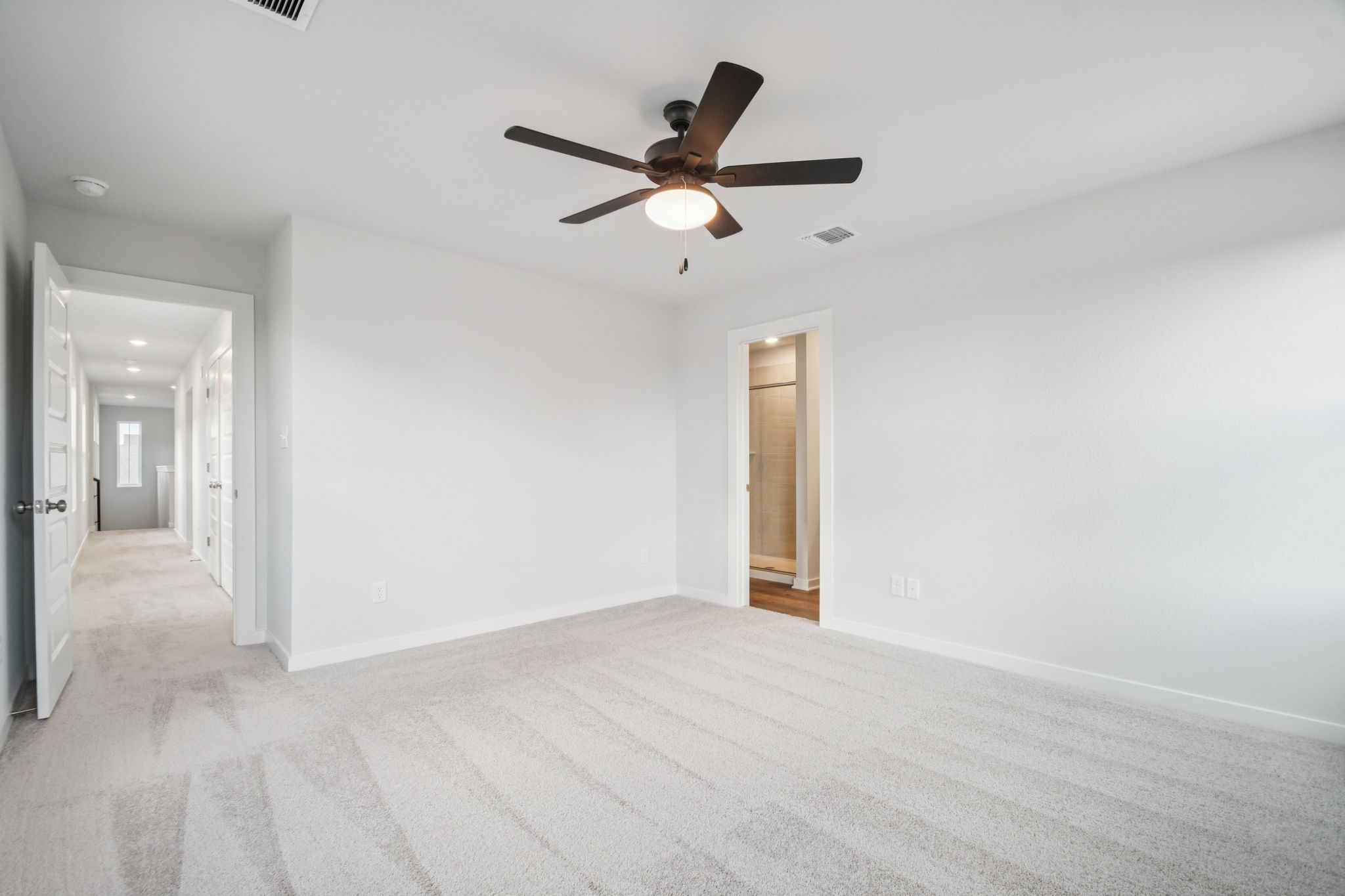 A room with a ceiling fan and a door.