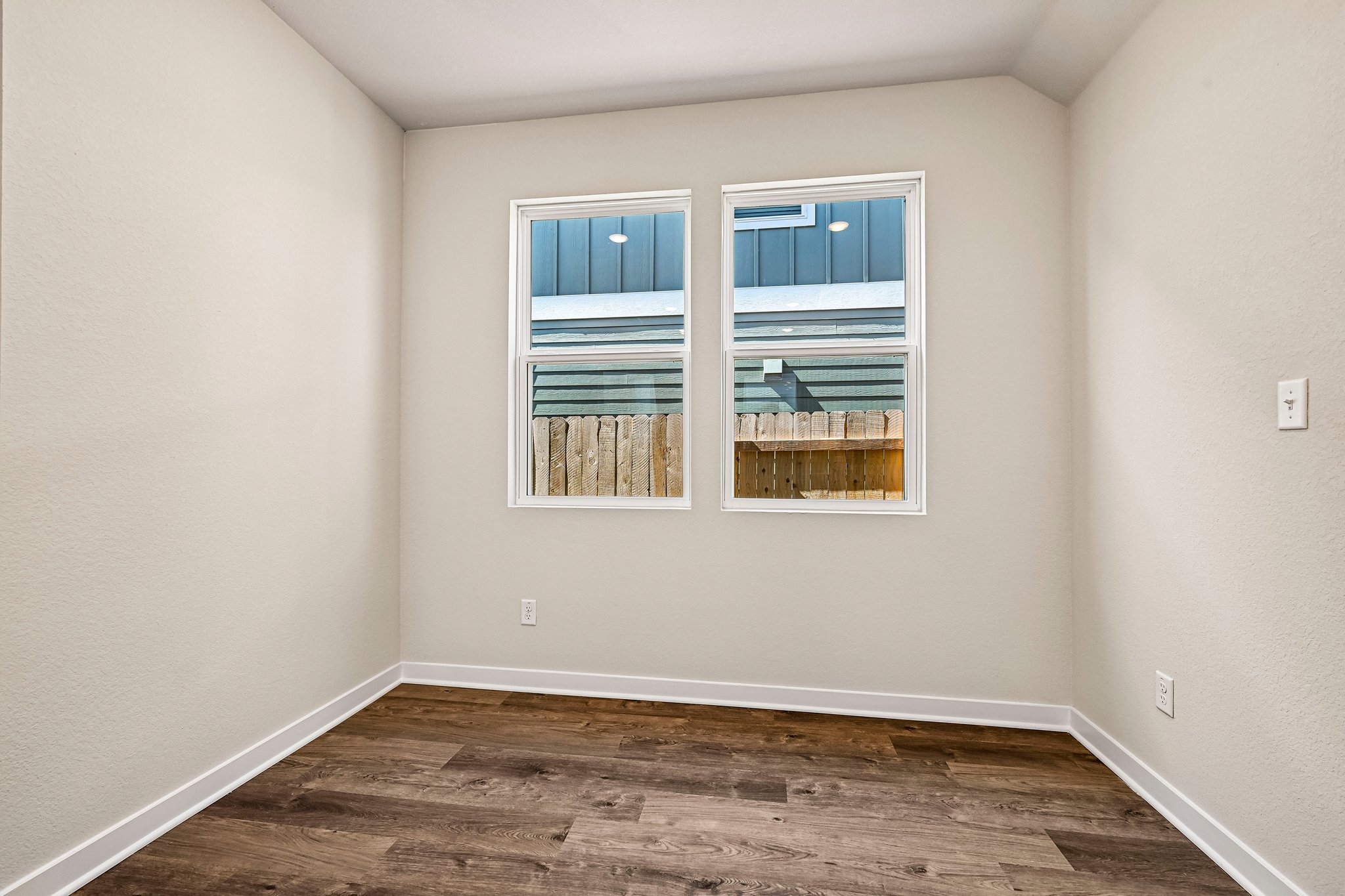 A room with a window and a wood floor.