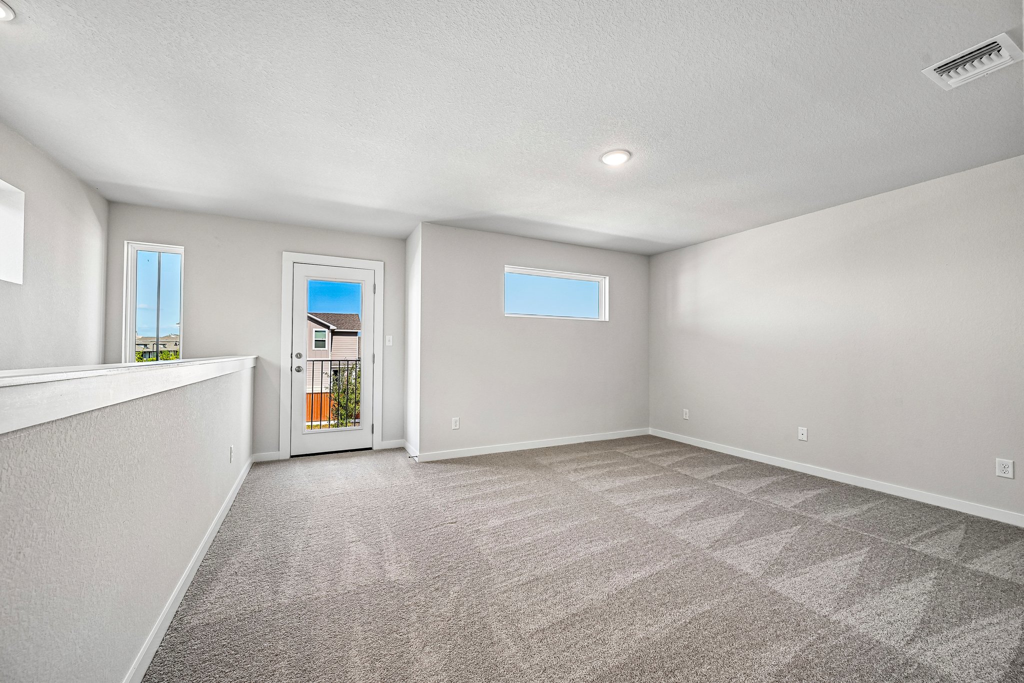 A large empty room with a white floor and a white door.