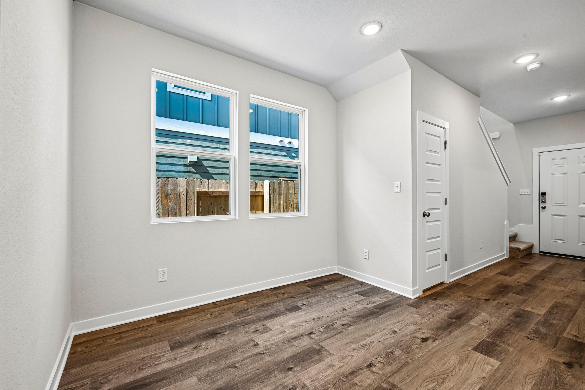 A room with white walls and a wood floor with a window and a wood floor with a wood.