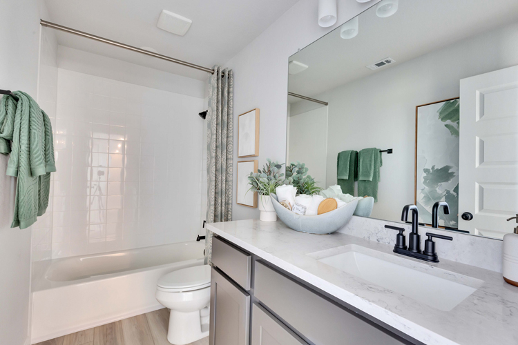 A bathroom with a tub sink and mirror.