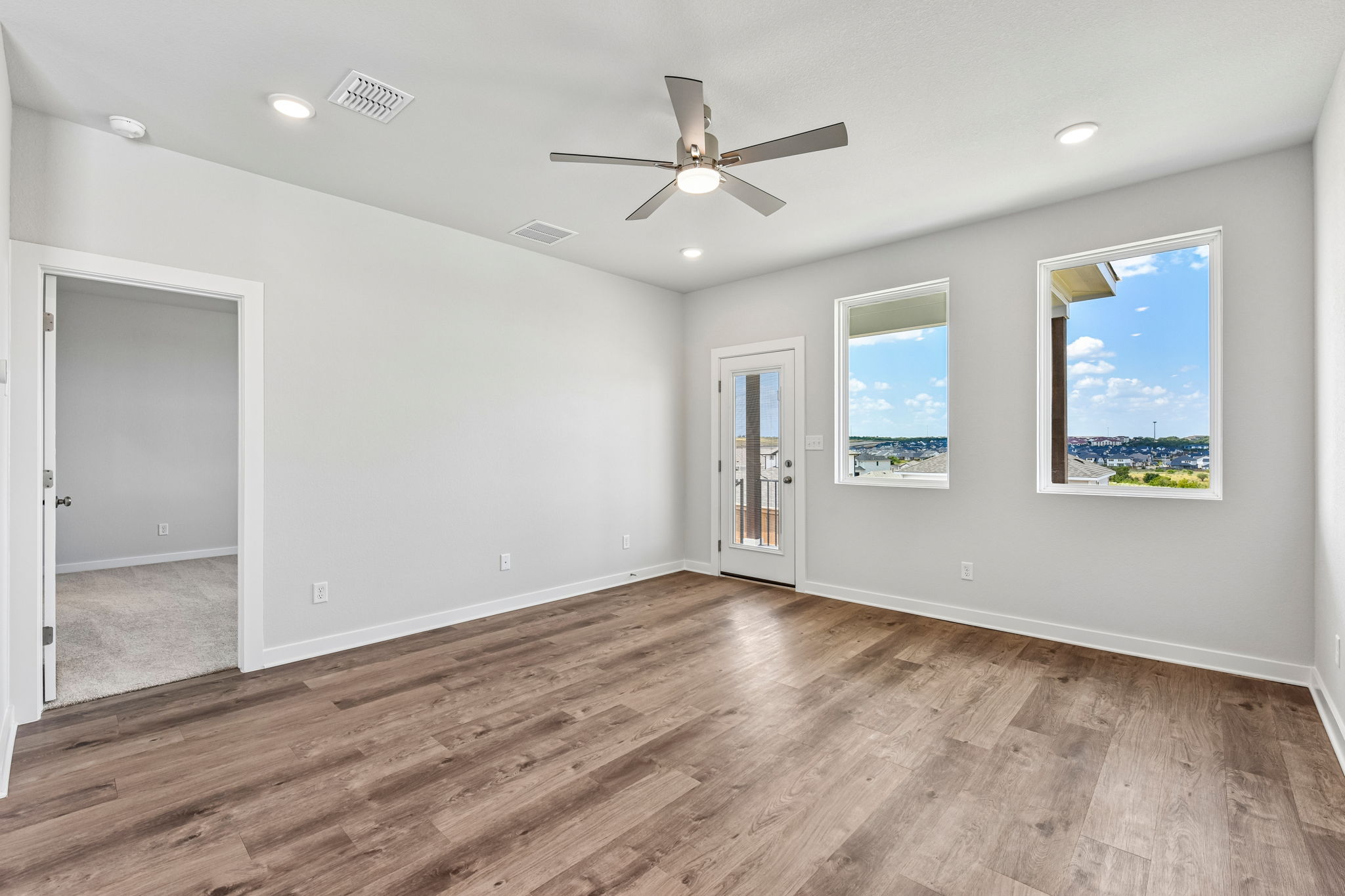 A room with a wood floor and a ceiling fan.
