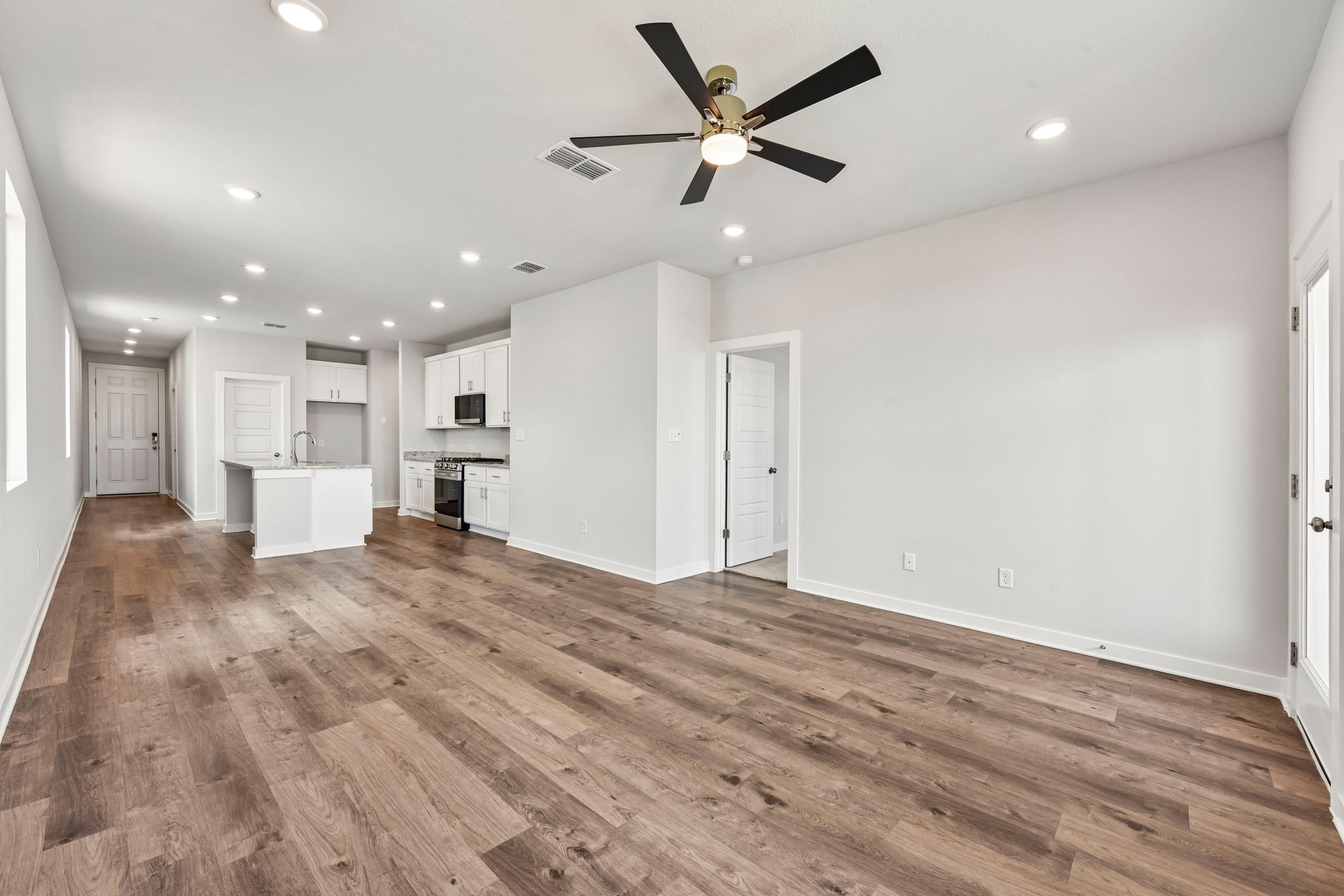 A large empty room with a wood floor and a ceiling fan.