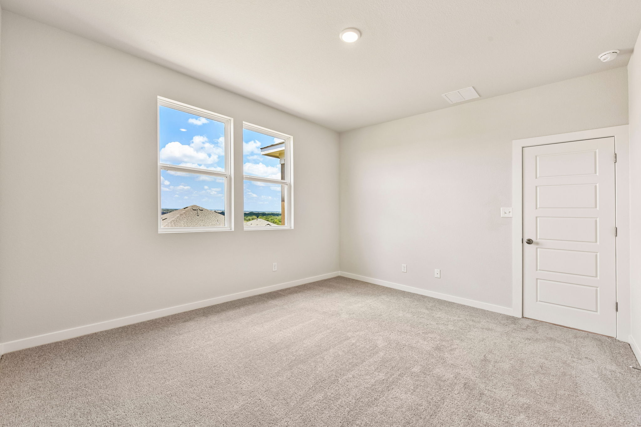A room with a door and a window with a view of the ocean.