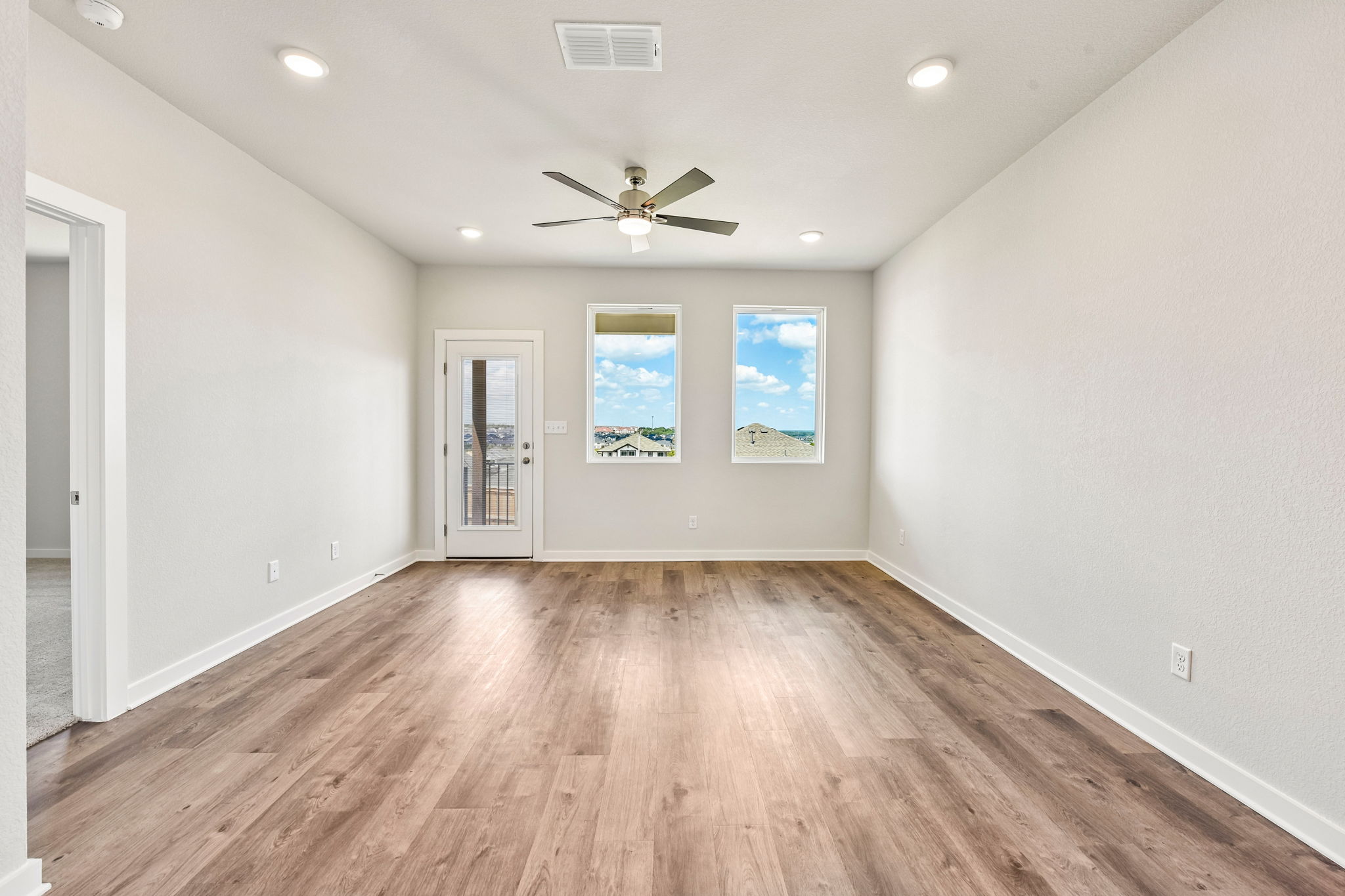 A room with a wood floor and a ceiling fan.
