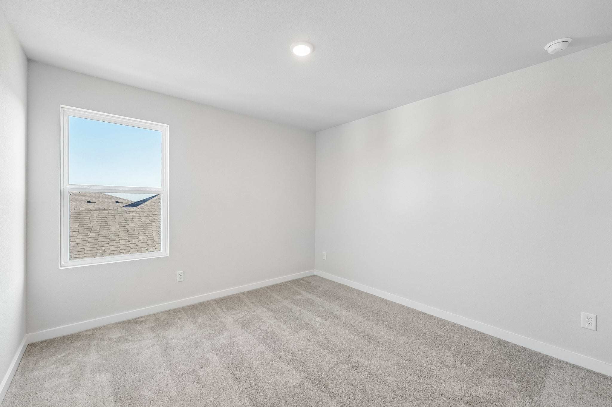 A room with a window and a white wall.