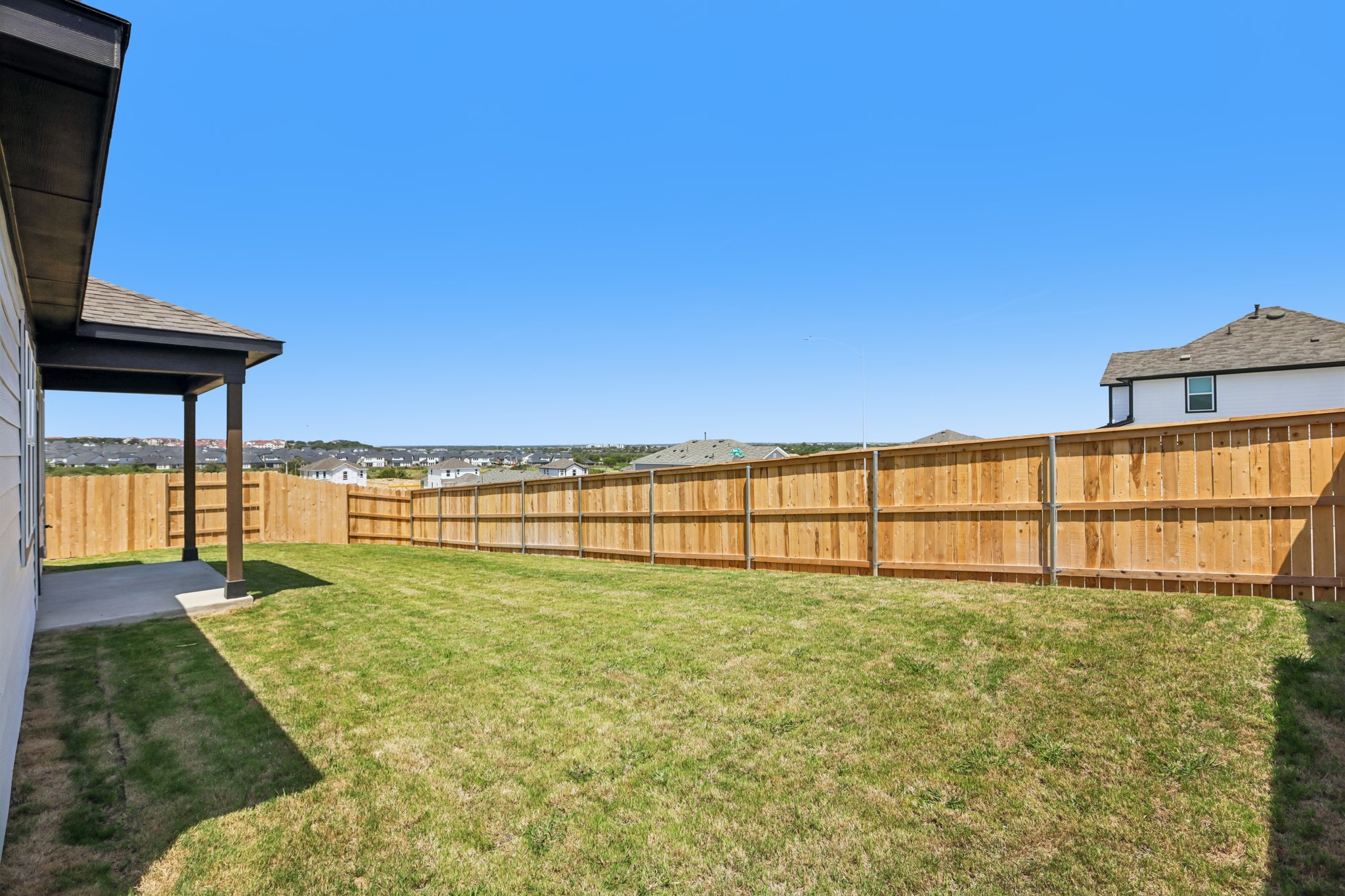 A fenced in yard with a wood fence and a building in the background.