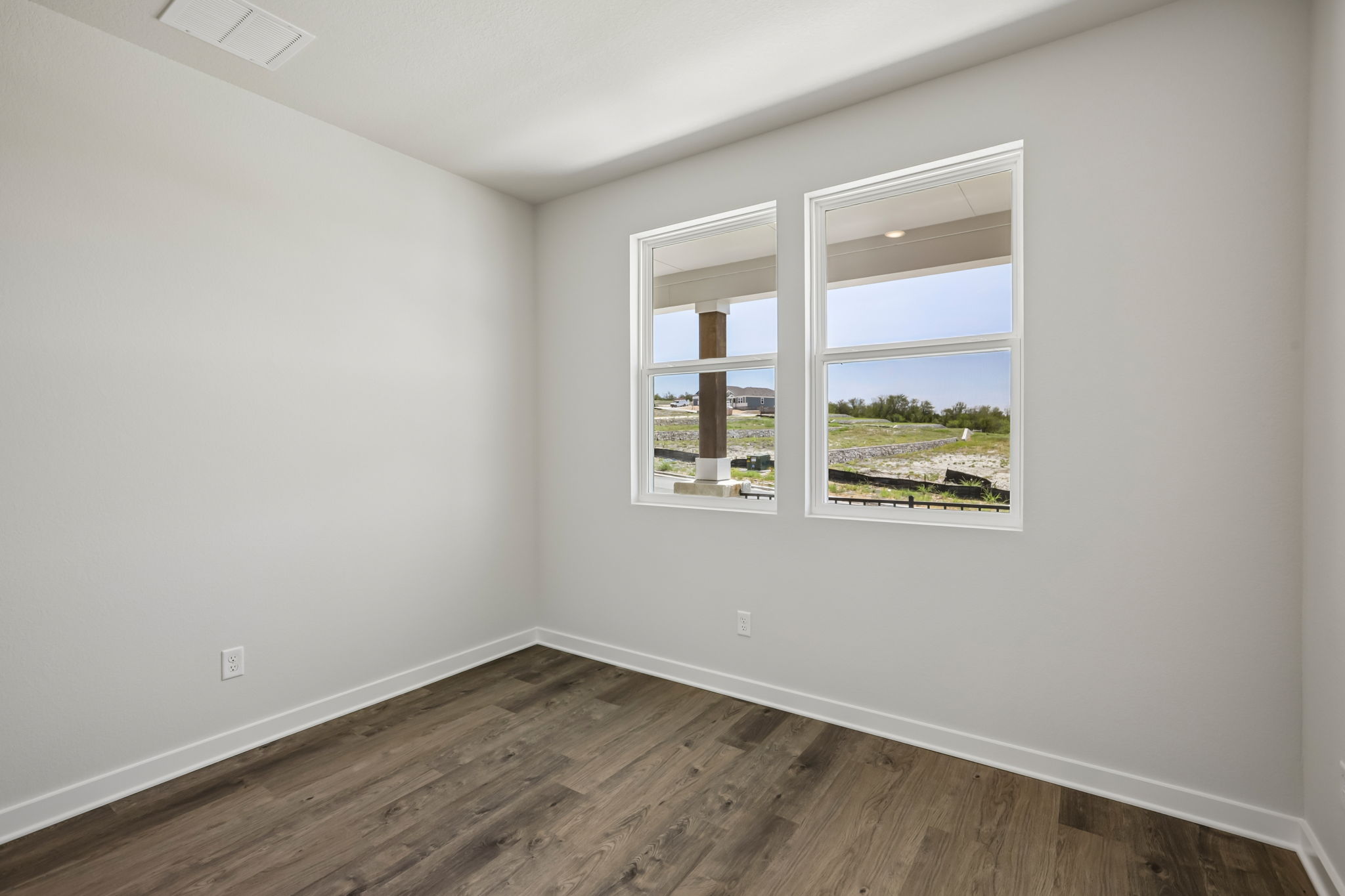 A room with a window and a wood floor.