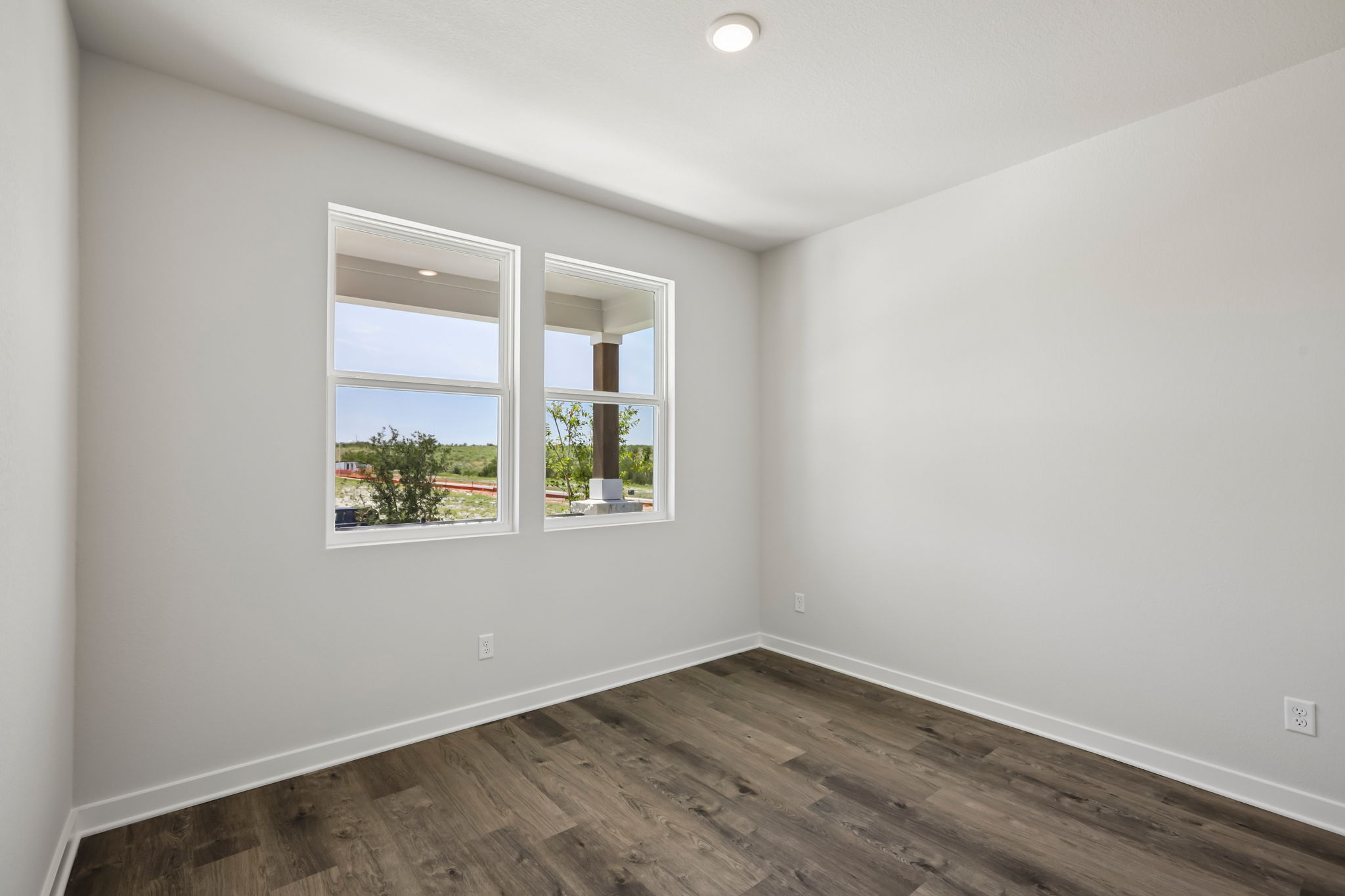 A room with a wood floor and a window with a view of trees.