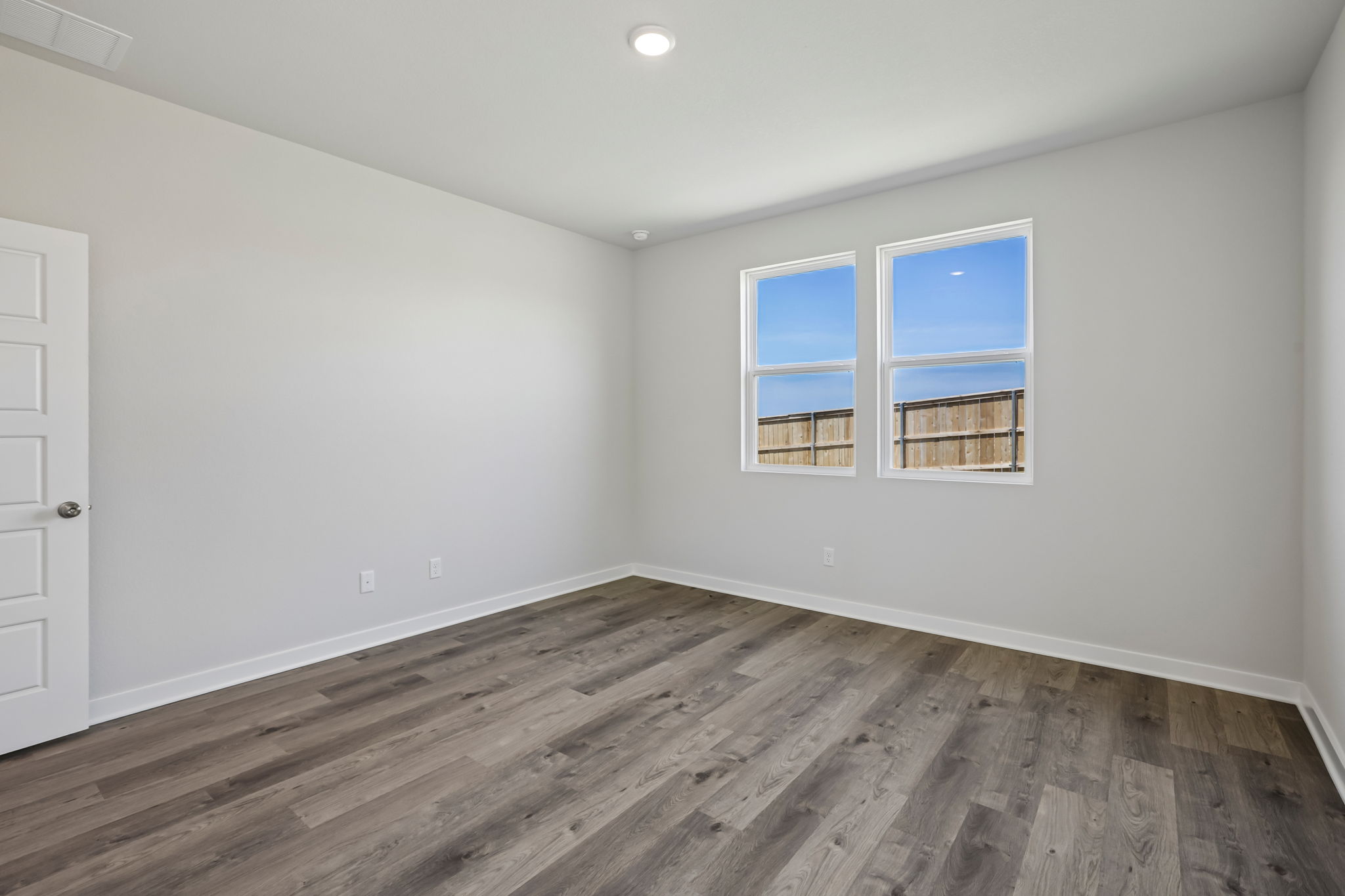 A room with a wood floor and windows.